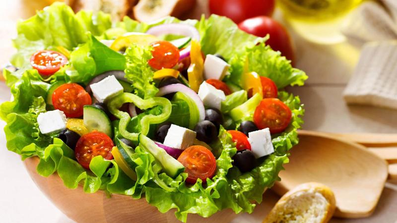 Một chén salad rau xanh trộn với các loại hạt, phô mai, ớt chuông, cà chua, dưa leo